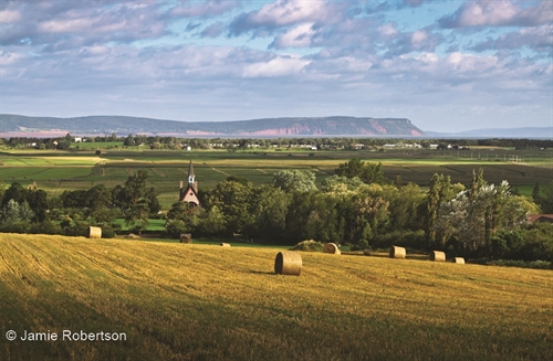 This is beautiful Grand Pré with the Bay of Fundy and Cape Blomidon in the background.  A gorgeous spot in Nova Scotia.